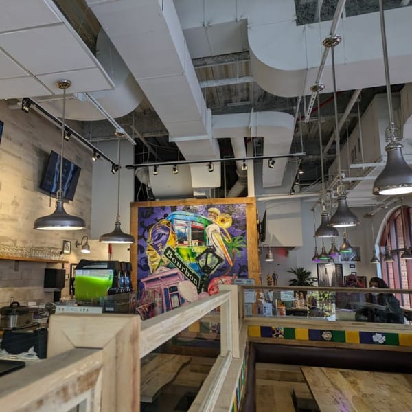 Creole 2 Geaux interior with a large colorful mural, exposed ductwork, and industrial pendant lights.