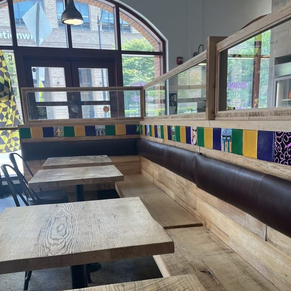 Creole 2 Geaux dining area with wooden tables, benches, and colorful Creole-themed wall decor.
