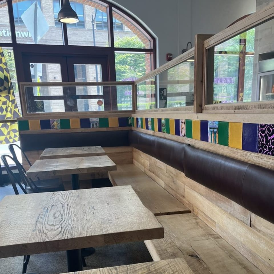 Creole 2 Geaux dining area with wooden tables, benches, and colorful Creole-themed wall decor.