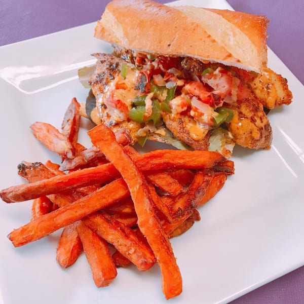 Creole 2 Geaux shrimp po'boy with colorful toppings and a side of sweet potato fries.