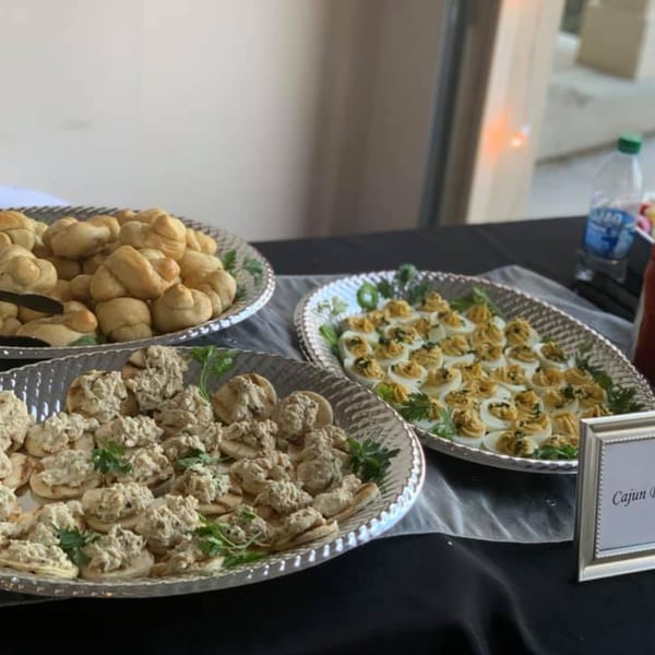 Creole 2 Geaux catering spread with deviled eggs, chicken salad bites, and dinner rolls.