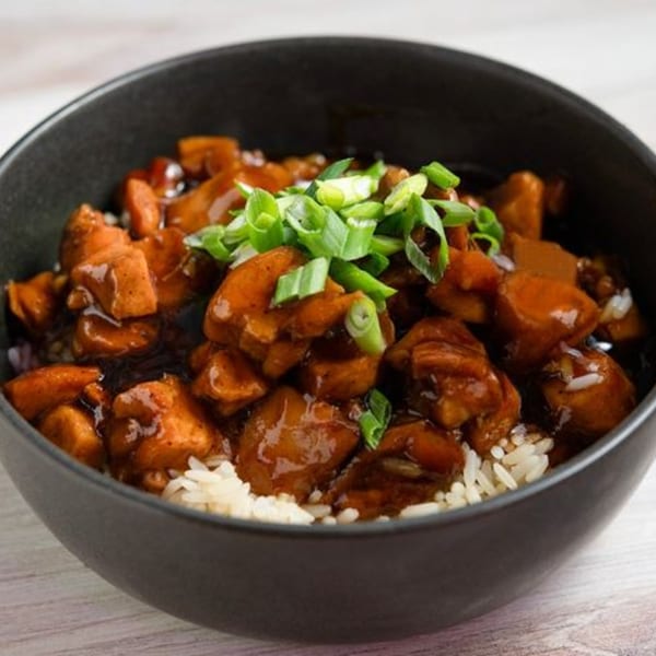 Creole 2 Geaux's chicken and rice bowl, garnished with fresh green onions.