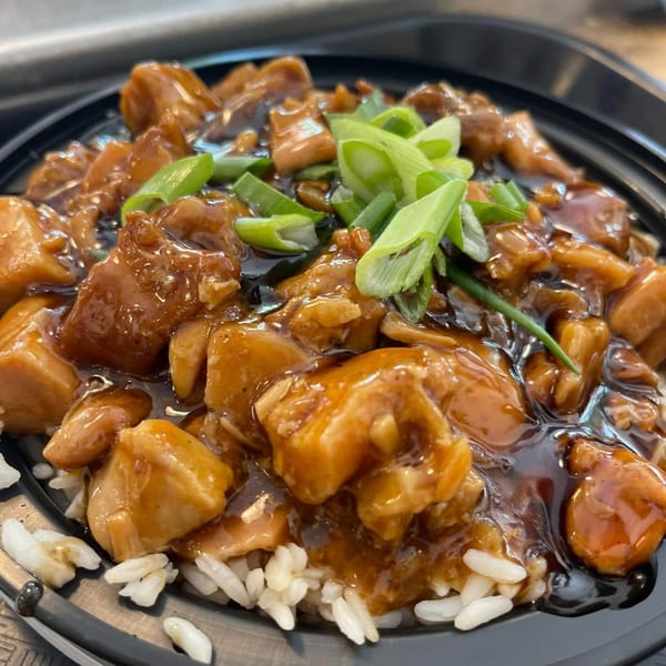 Creole 2 Geaux's chicken and rice dish, topped with a rich dark sauce and fresh green onions.