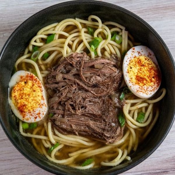 Creole 2 Geaux's ramen with shredded beef, noodles, green onions, and two seasoned boiled eggs.